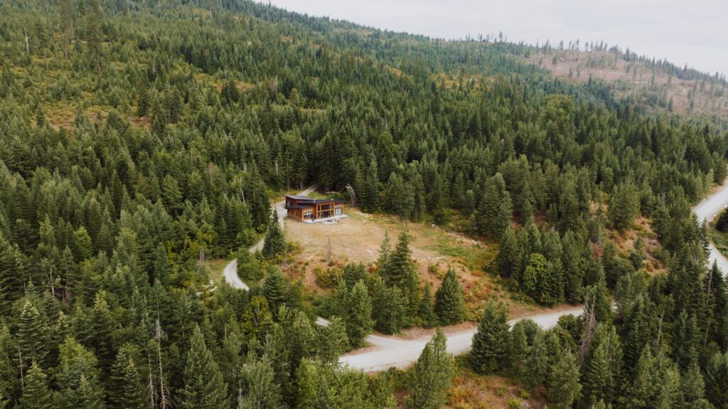 Aerial view of a rural home in a dense pine forest — wildfire preparedness setting