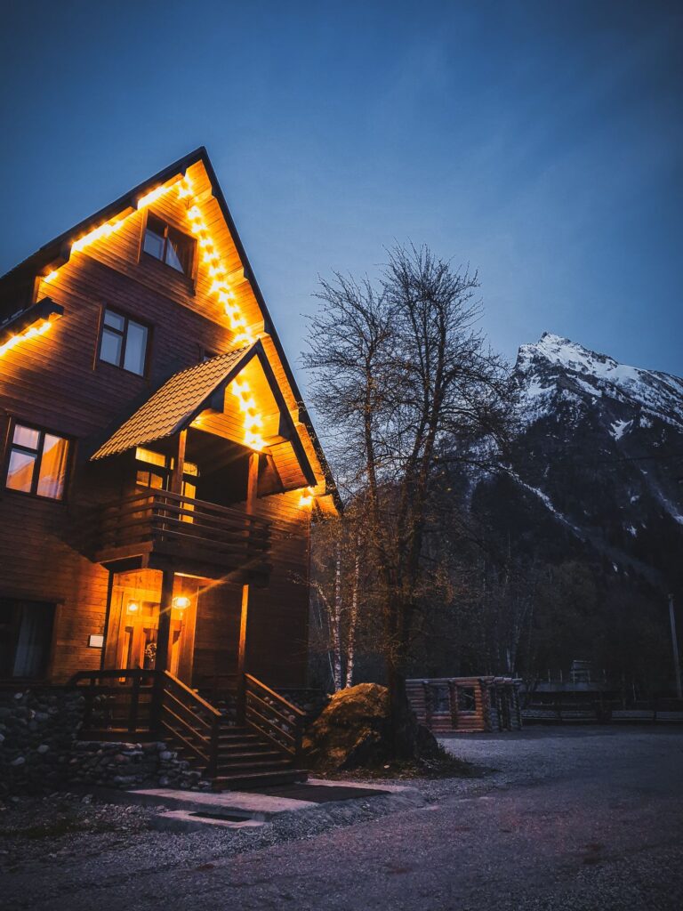 Cozy mountain chalet with warm interior lights against snowy mountain backdrop